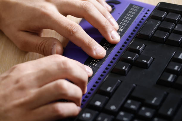 Close up of hands using a braille computer display.